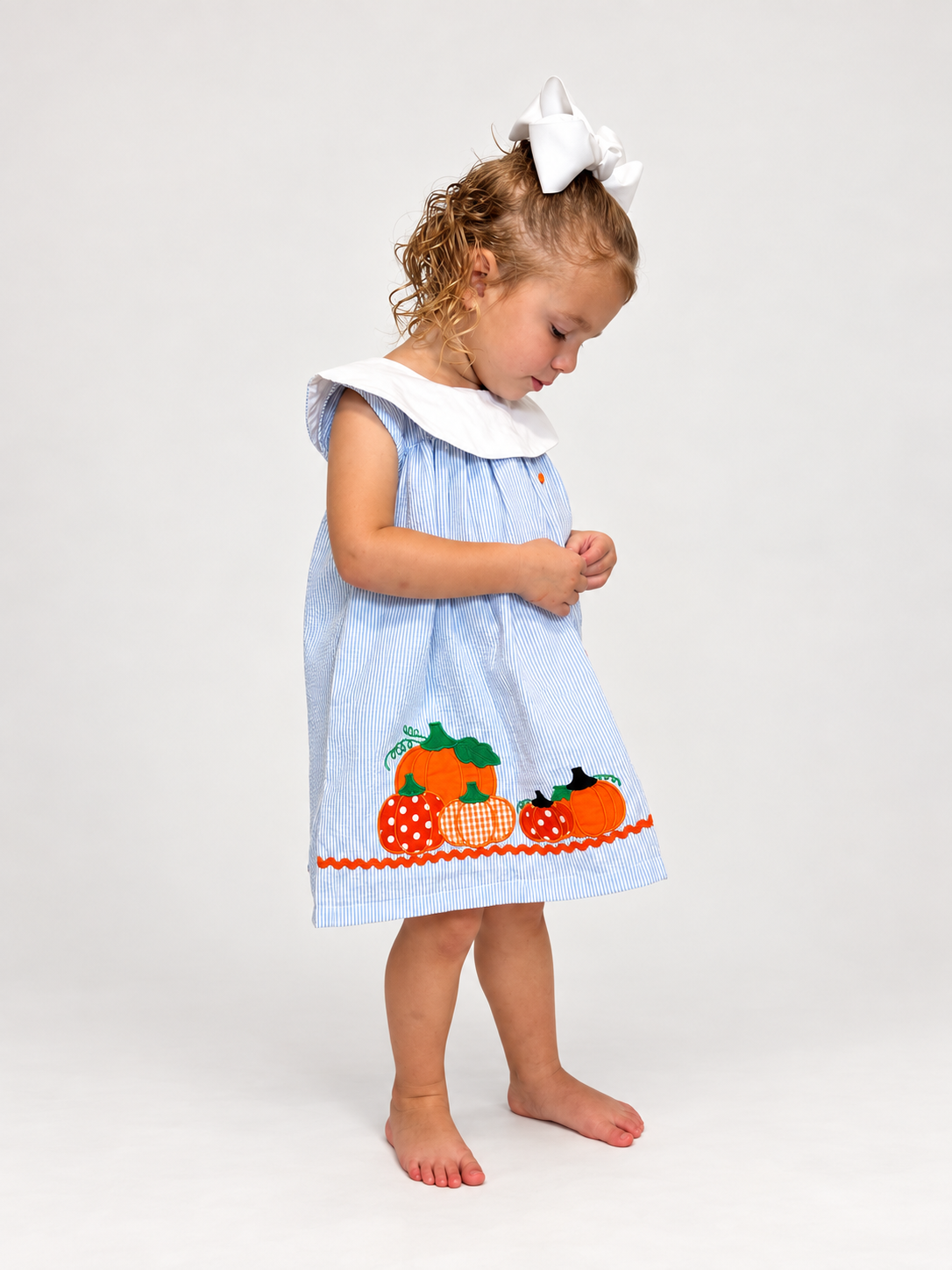 Girl in The Pumpkin Patch Dress looking down, side view