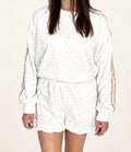 Woman wearing The Sutton Lounge Set, ivory dotted sweatshirt with tan sleeve stripes and ruffle-hem shorts, close-up front
