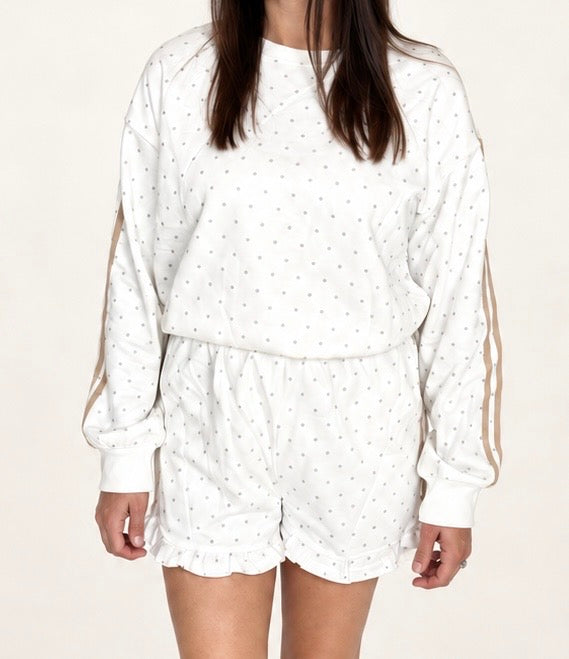 Woman wearing The Sutton Lounge Set, ivory dotted sweatshirt with tan sleeve stripes and ruffle-hem shorts, close-up front