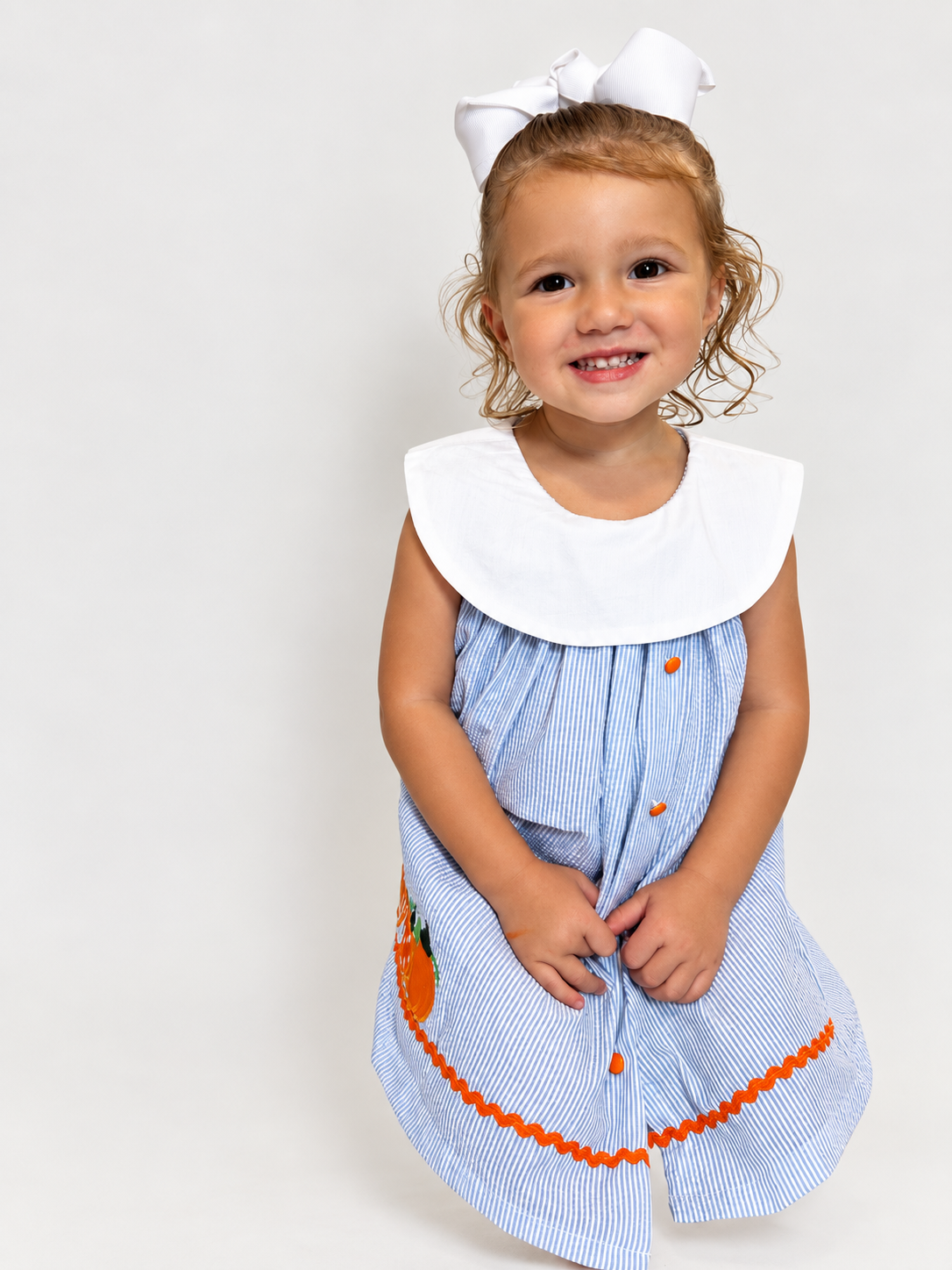 Girl in The Pumpkin Patch Dress smiling, sitting