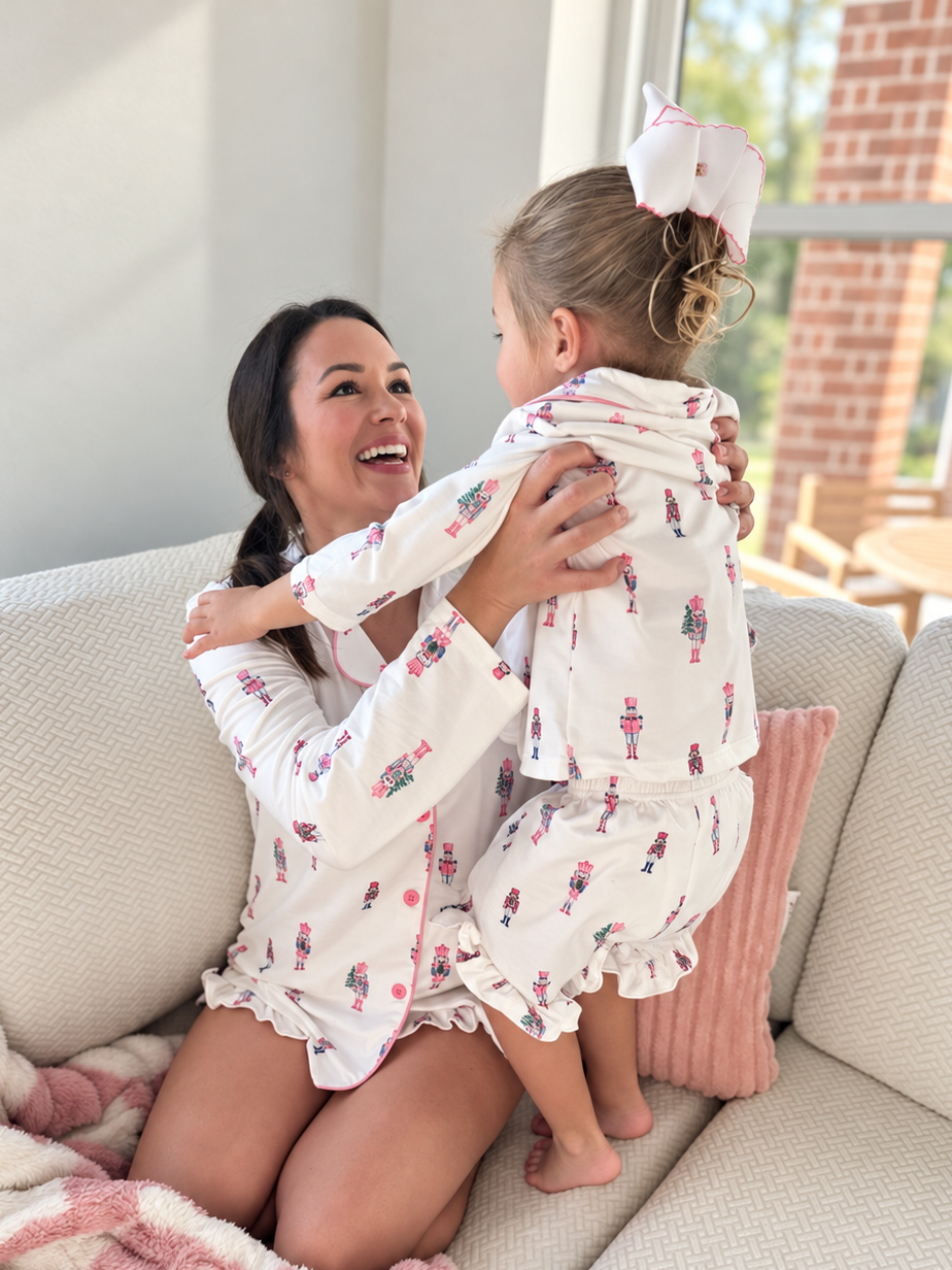 Mom lifting her daughter, both in matching Sugar Plum Fairy pajamas