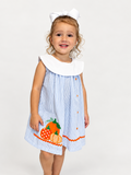 Girl wearing The Pumpkin Patch Dress, blue seersucker with white collar and pumpkin applique