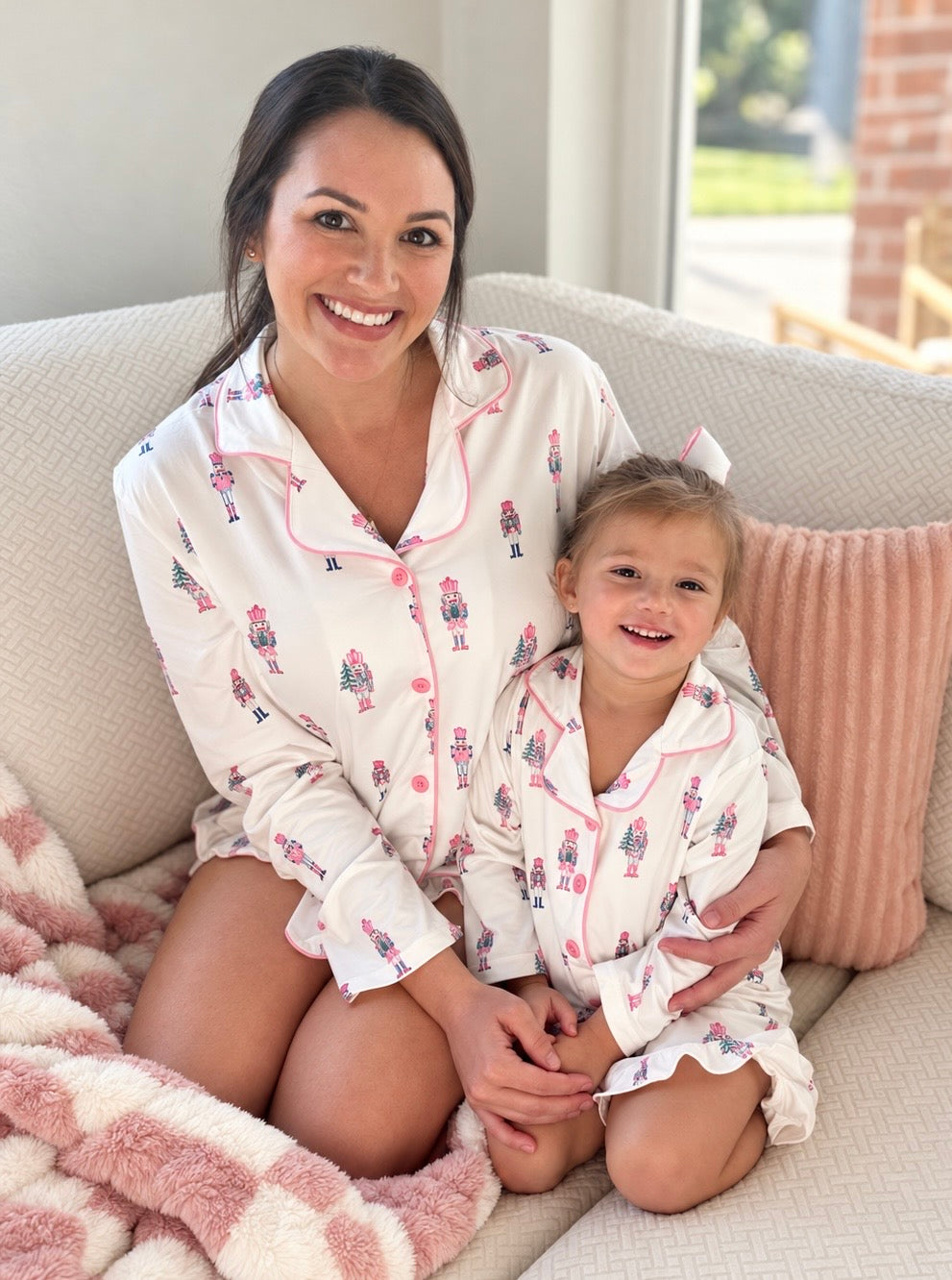 Daughter and mom in matching Sugar Plum Fairy nutcracker pajamas on a sofa