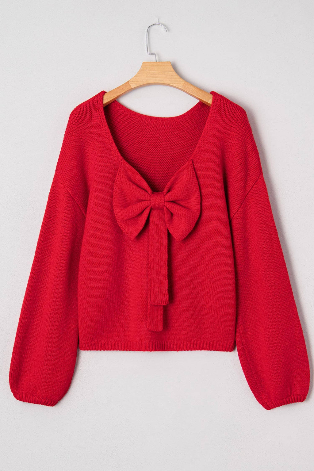 The Belle Bow Sweater on a hanger, back view showing the bow