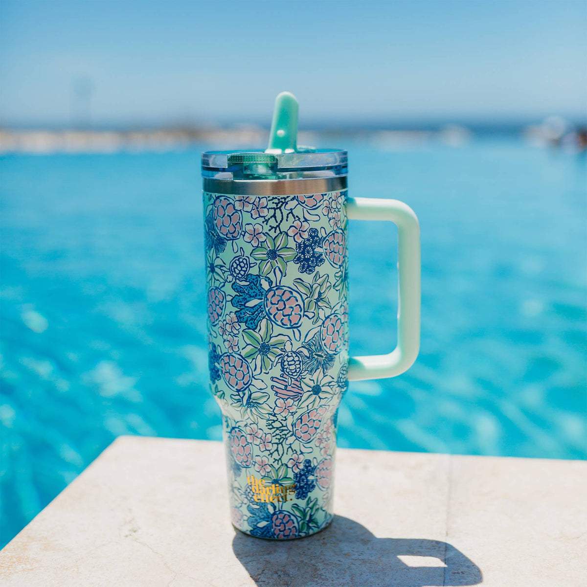 The Coastal Cove Tumbler, a seafoam 40 oz tumbler with sea turtles, coral and flowers and a mint flip straw